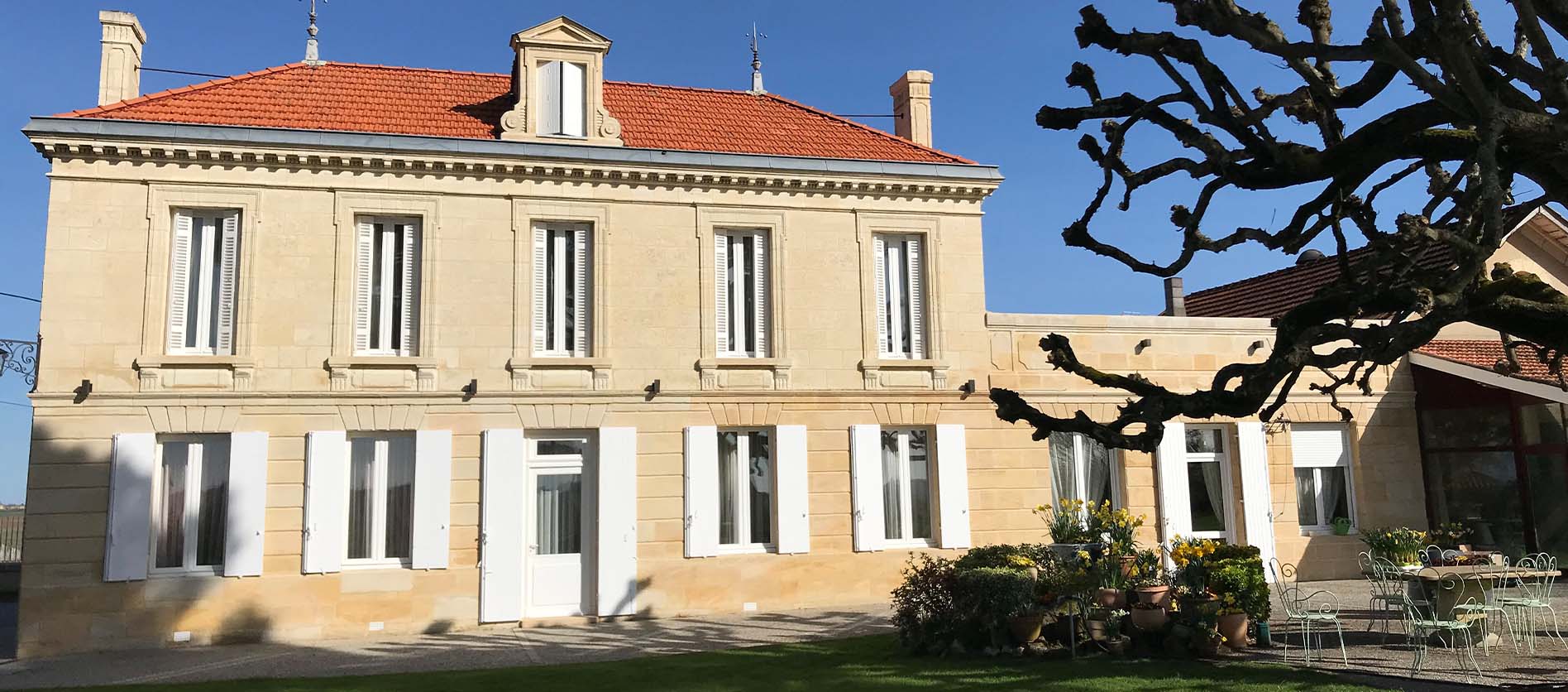 The Château Belair Coubet, a traditional stone estate with white shutters, a terracotta-tiled roof and landscaped gardens.
